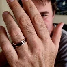 Rose gold and jarrah mens ring on a hand