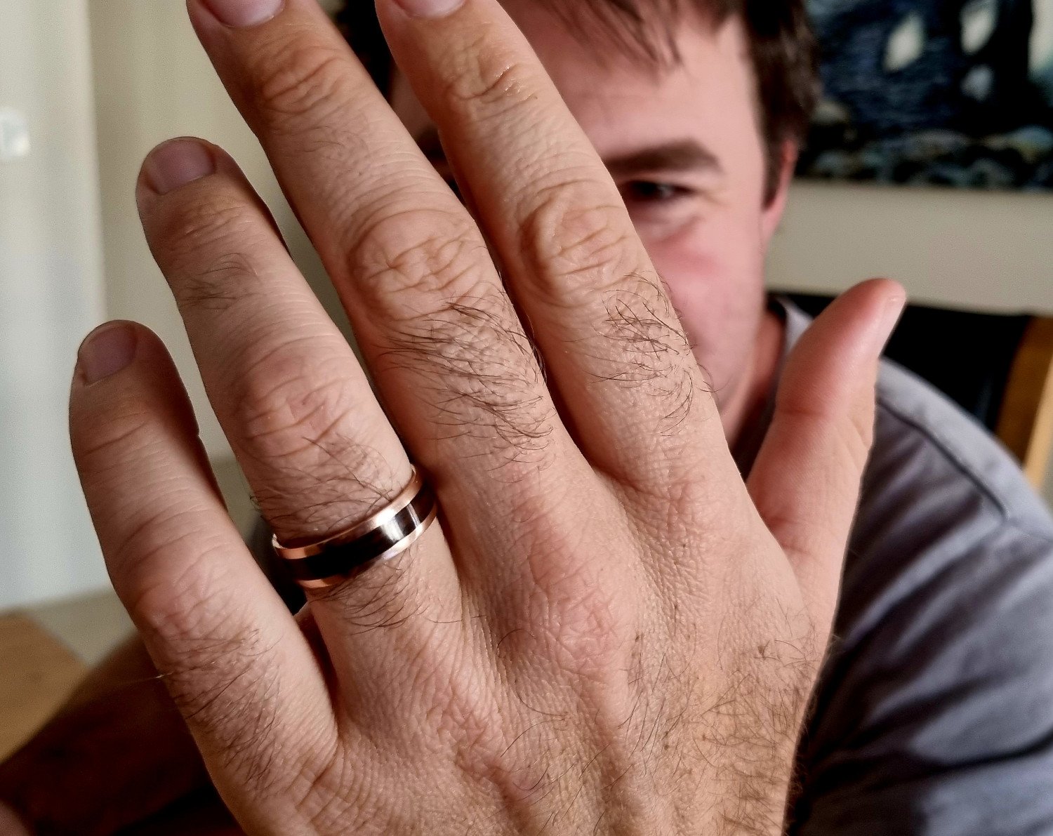 Rose gold and jarrah mens ring on a hand